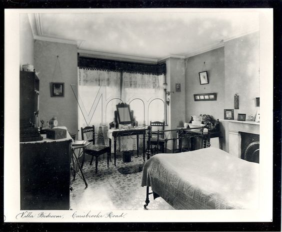 Victorian bedroom showing gas light lamp in the window. Linoleum flooring and fireplace is also shown.