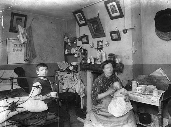 Victorian slum interior showing gas light lamps above the fireplace