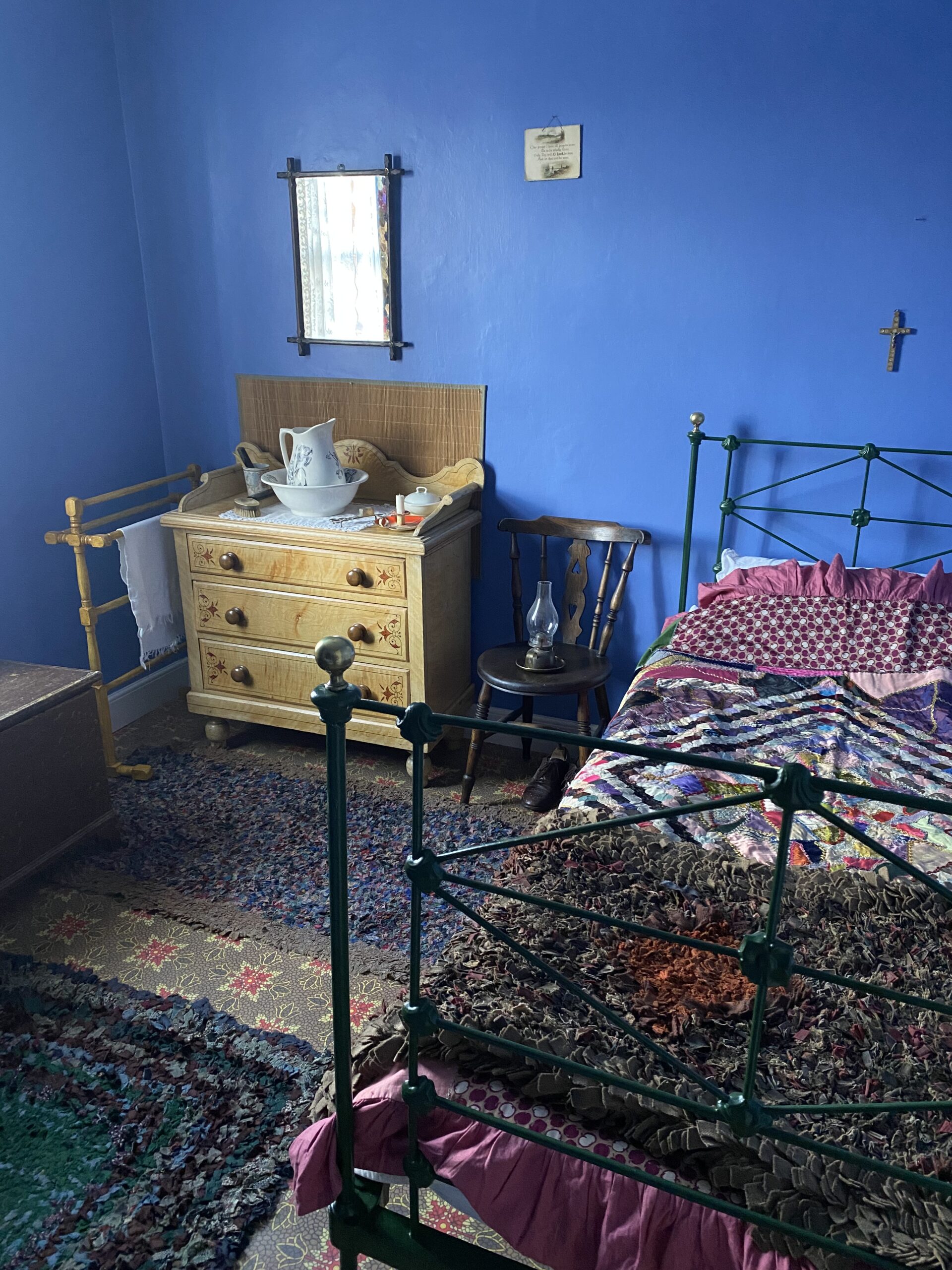 Victorian bedroom with blue painted walls and rag rugs