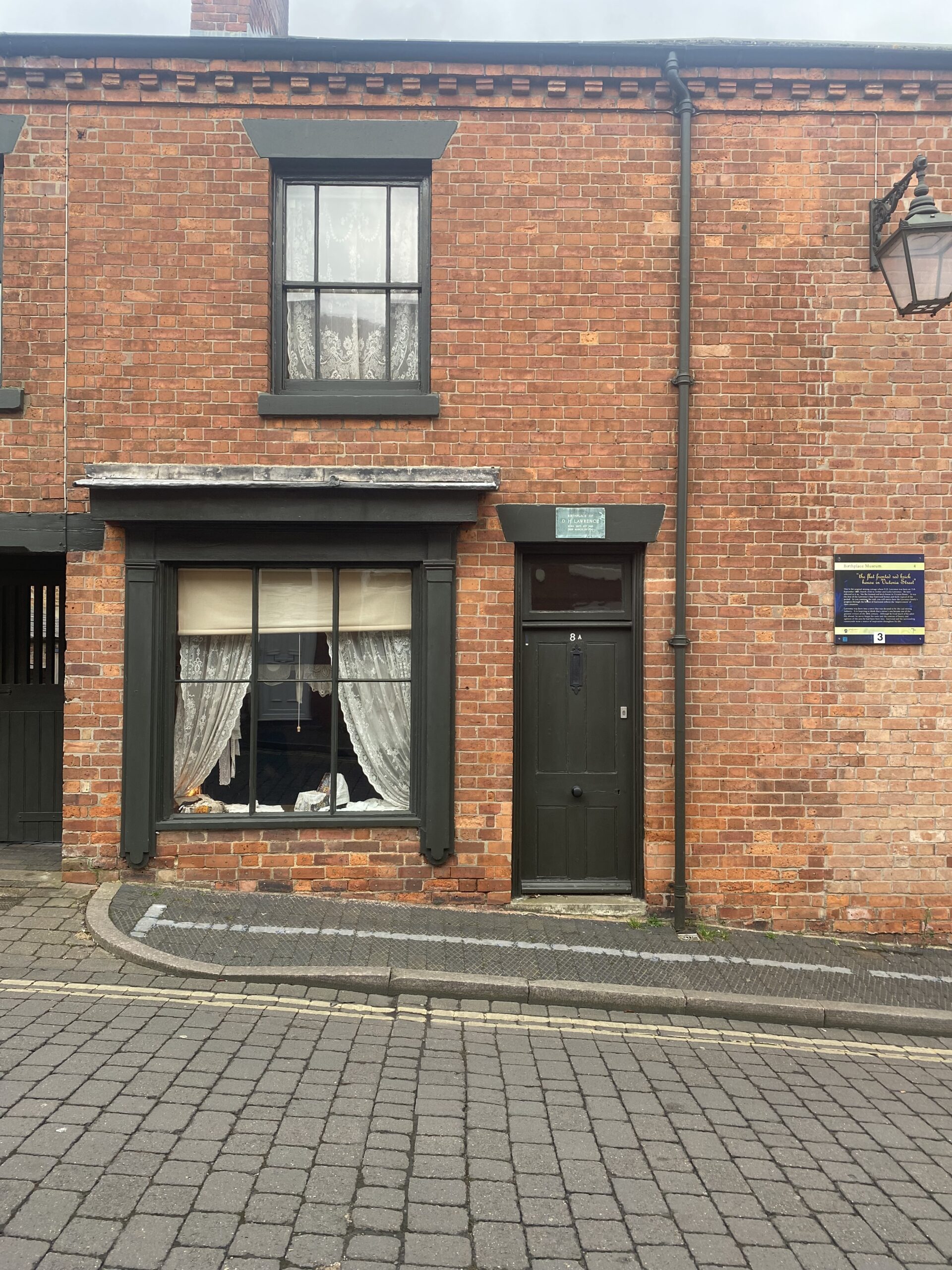 Victorian paint exterior - dark green windows and downpipe at DH Lawrence's Birthplace Museum, which is terraced house with shop window