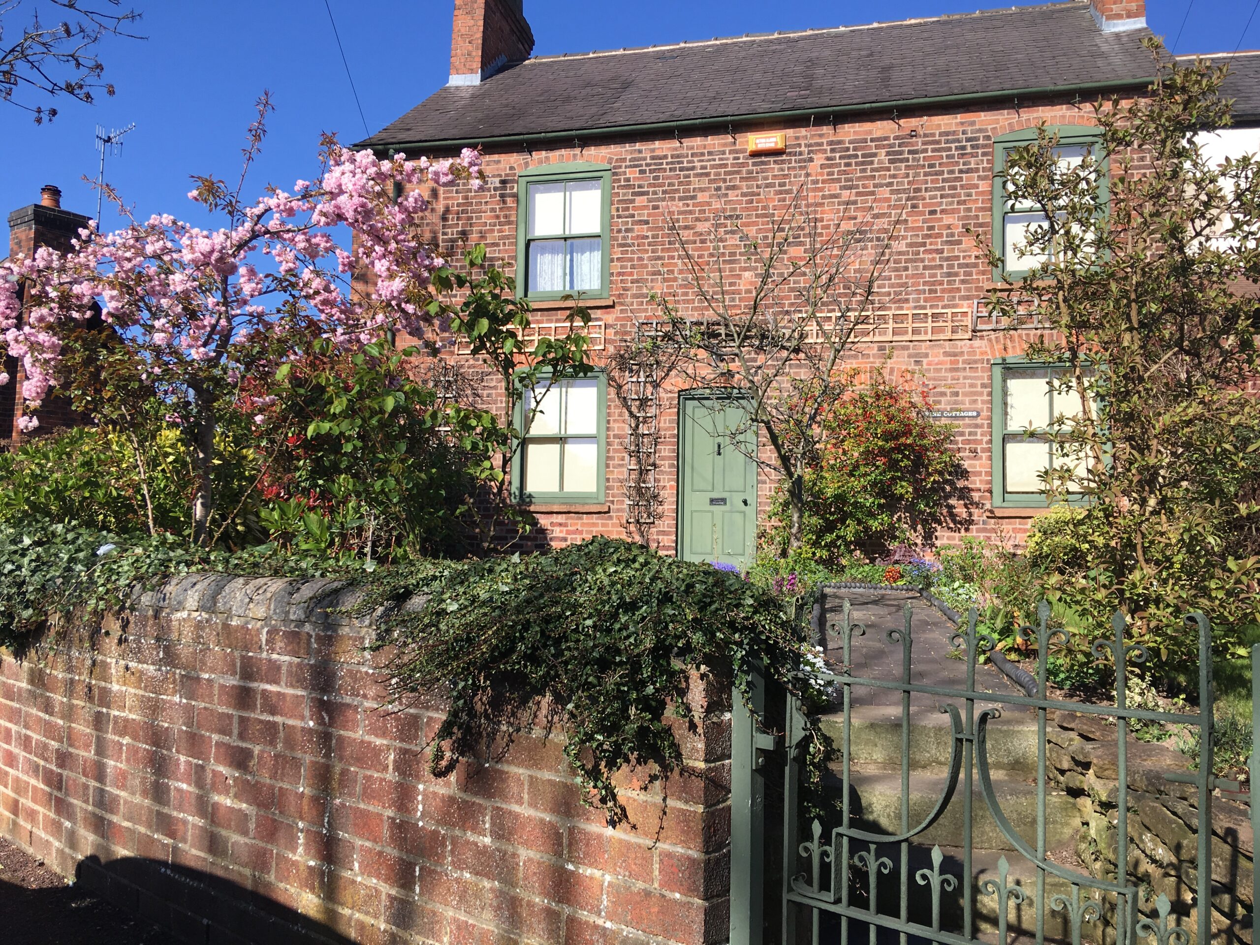 Victorian cottage with mid green windows, front door and gate.