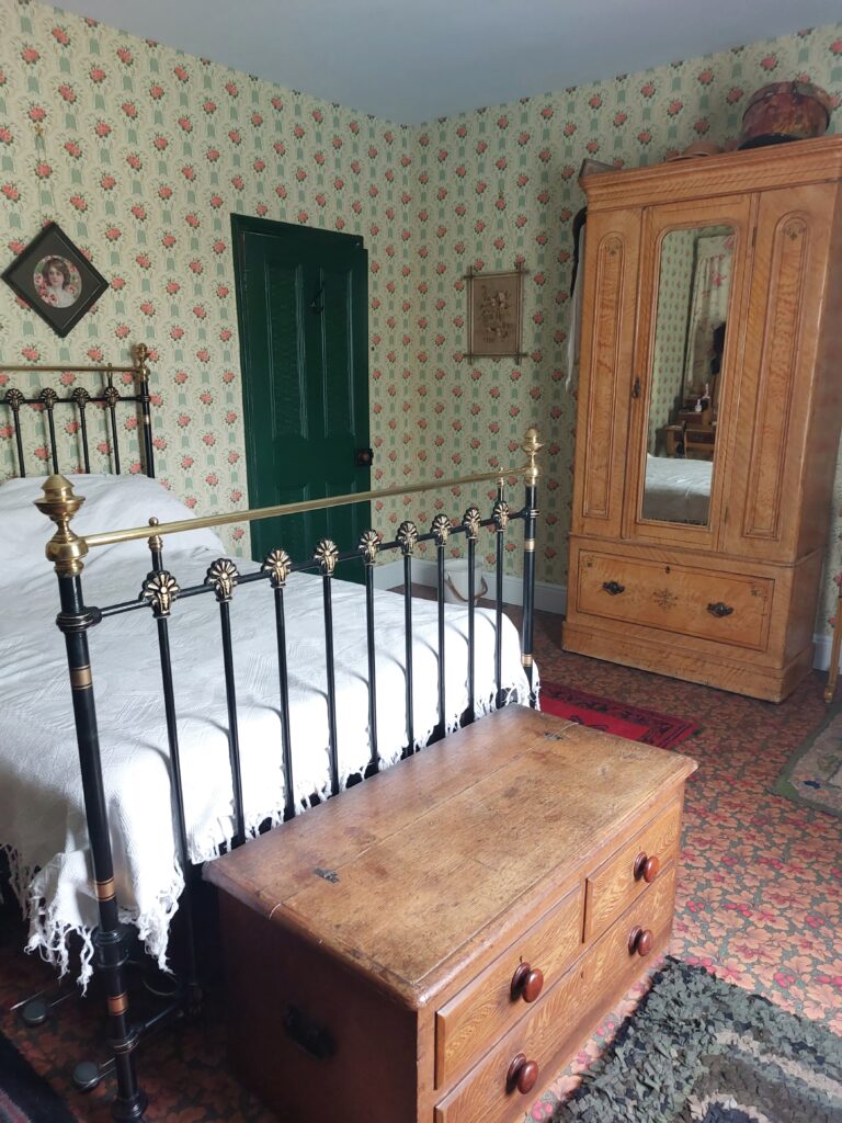 Victorian bedroom with recreated Edwardian wallpaper and brass and iron bed