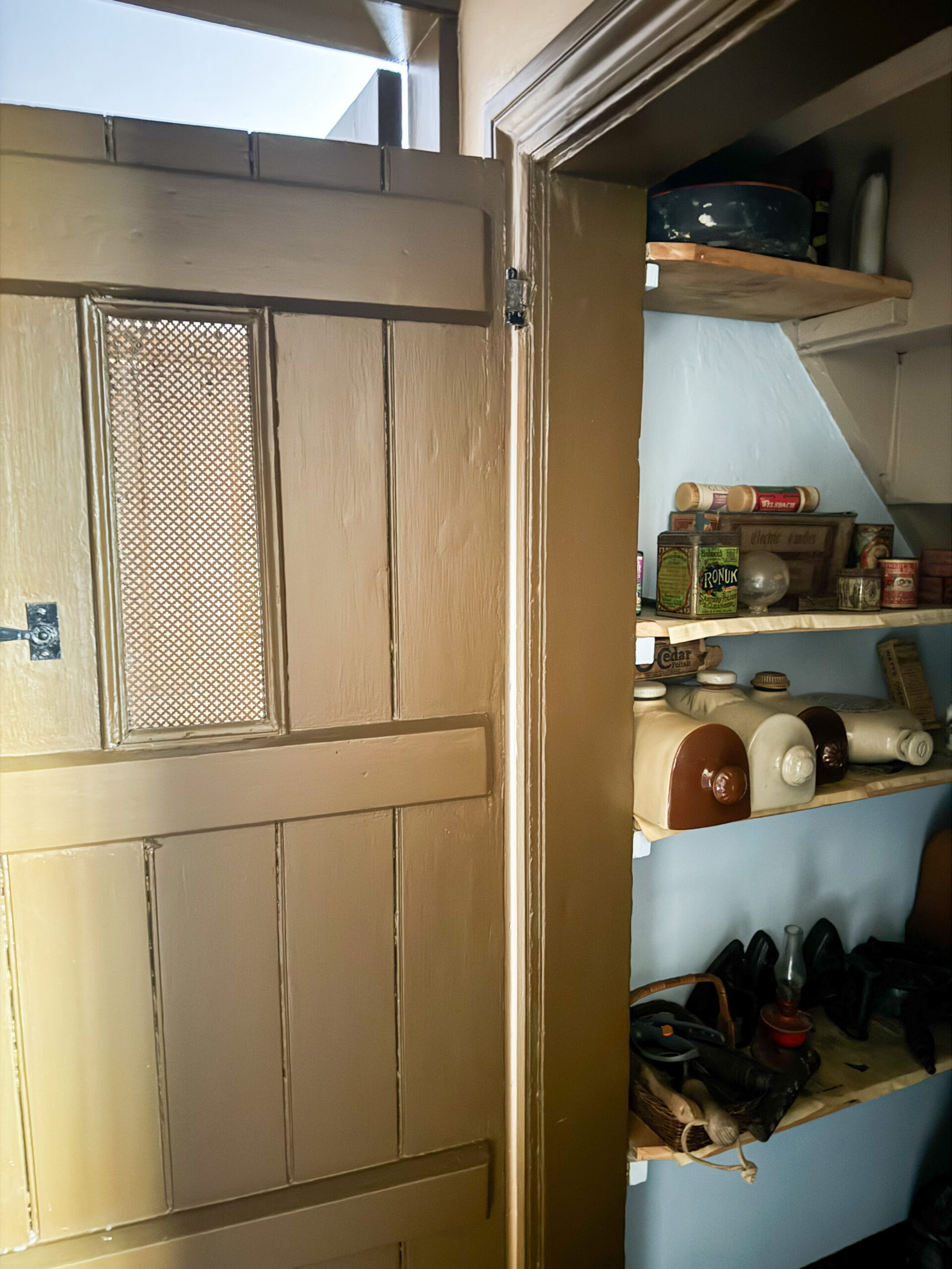 Victorian understairs storeroom with household products, irons and sewing machine.